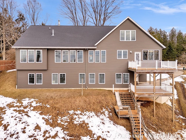 back of house with roof with shingles, a deck, and stairs