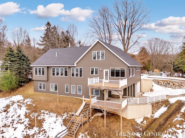 snow covered property with stairway and a wooden deck