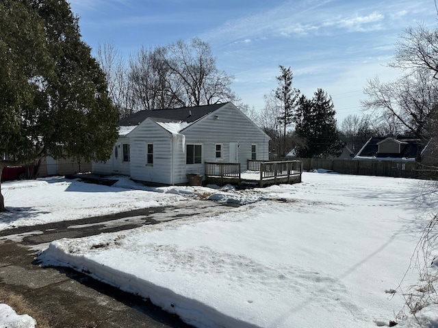 snow covered house with fence and a deck