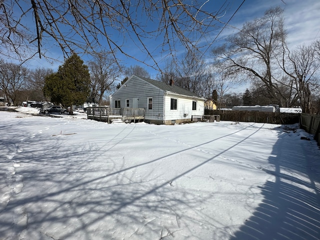 view of snow covered exterior with a deck and fence