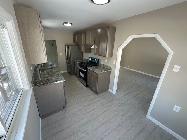 kitchen with light wood-type flooring, freestanding refrigerator, a sink, and range with gas cooktop