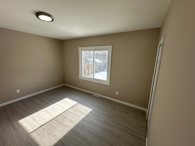 spare room with baseboards and wood finished floors