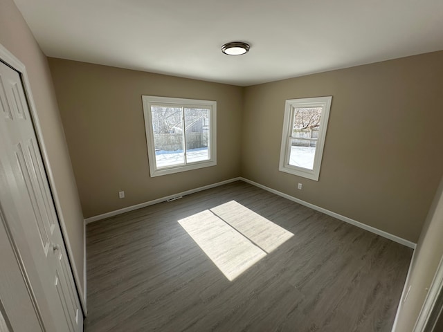 unfurnished bedroom featuring dark wood-style floors, a closet, and baseboards