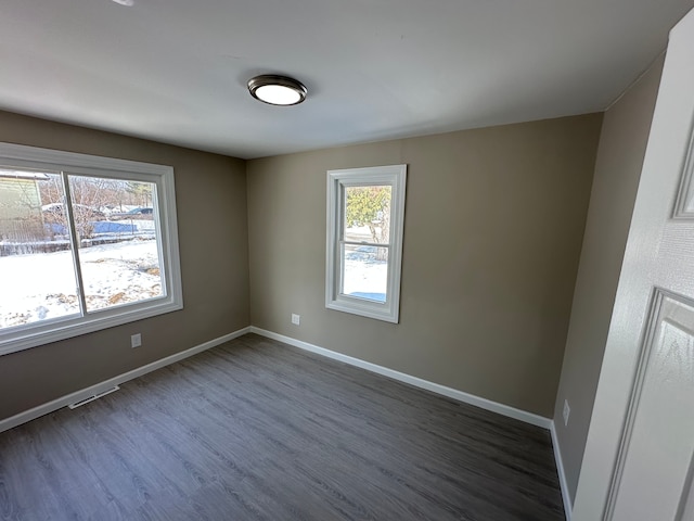 unfurnished room featuring baseboards and dark wood-type flooring