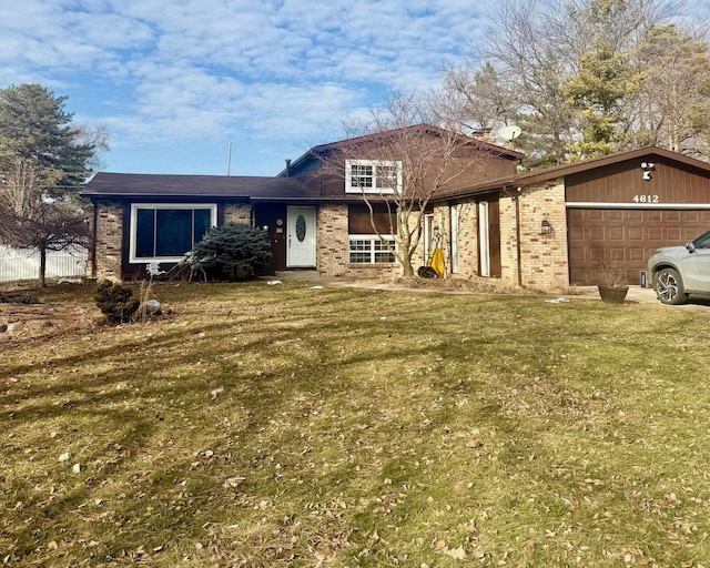 split level home featuring a garage, a front yard, and brick siding