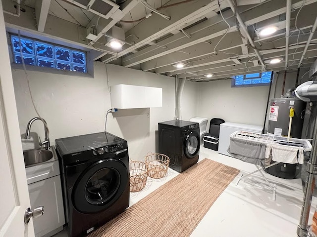 washroom with laundry area, water heater, a sink, and independent washer and dryer