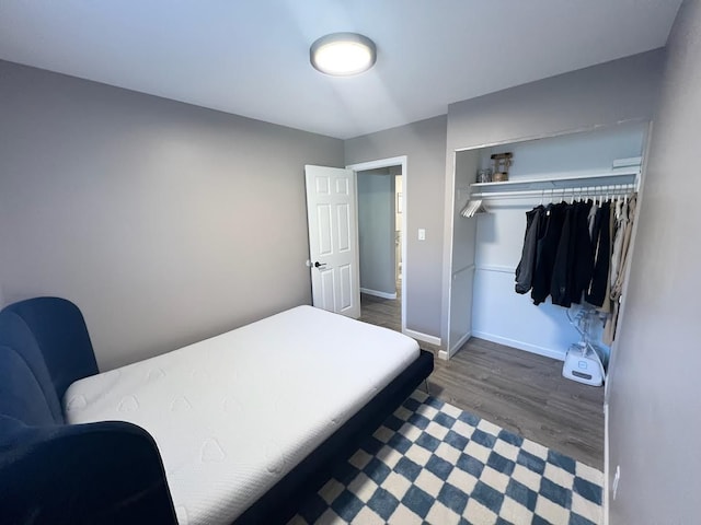 bedroom featuring a closet, wood finished floors, and baseboards