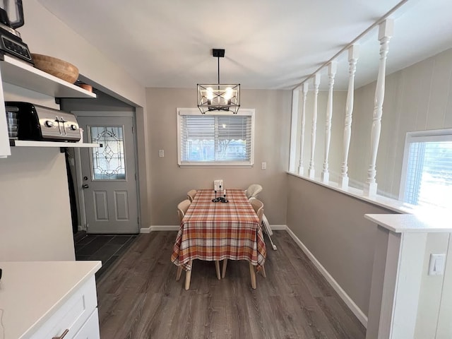 dining area with dark wood-type flooring, baseboards, and an inviting chandelier