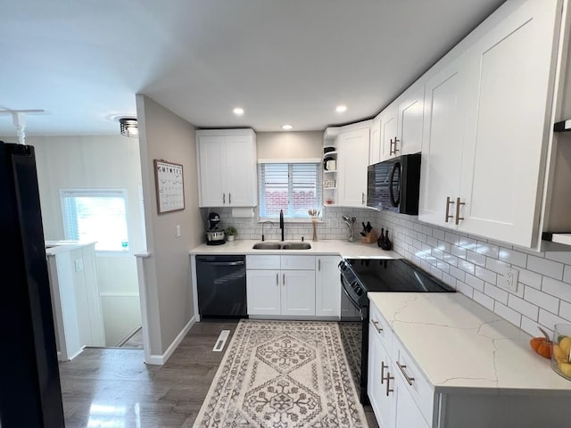 kitchen featuring white cabinets, a sink, light wood finished floors, and black appliances