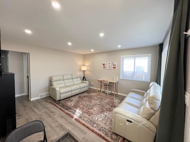 living area with recessed lighting, visible vents, baseboards, and wood finished floors