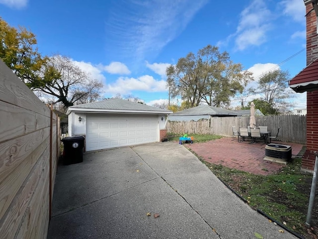 exterior space with a patio, a detached garage, an outbuilding, fence, and central AC