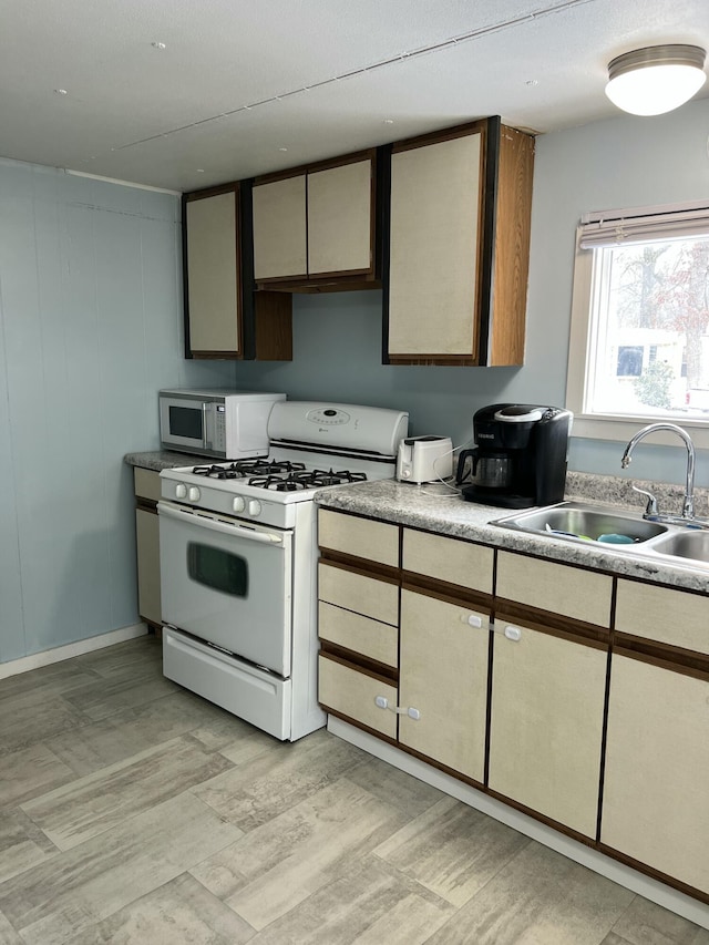 kitchen featuring light countertops, white appliances, light wood-type flooring, and a sink