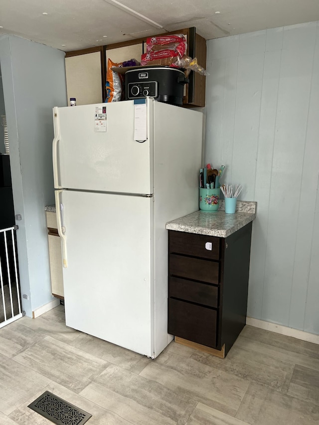 kitchen with visible vents, dark brown cabinets, light countertops, and freestanding refrigerator