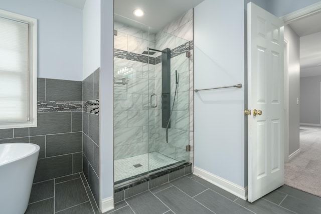 bathroom with a stall shower, a soaking tub, and baseboards