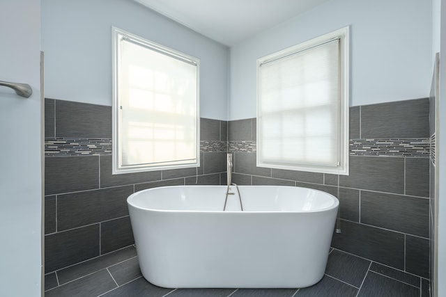 bathroom featuring tile patterned flooring, a soaking tub, and tile walls