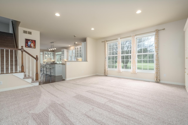 unfurnished living room with recessed lighting, visible vents, carpet, and stairs