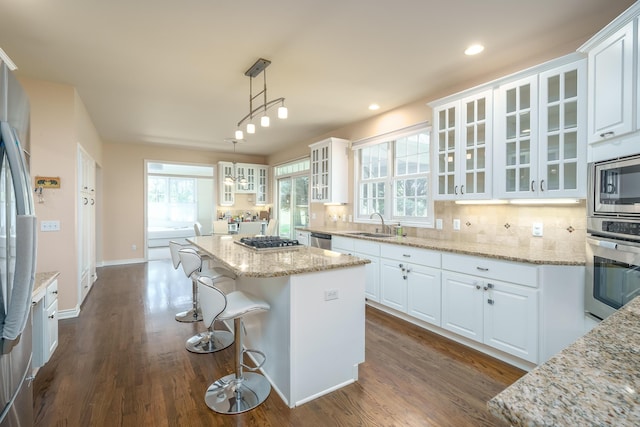 kitchen featuring white cabinetry, appliances with stainless steel finishes, decorative backsplash, and a center island