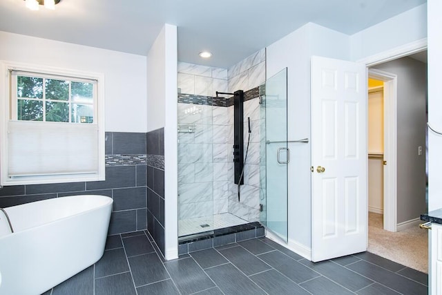 bathroom with a stall shower, a freestanding tub, and tile walls