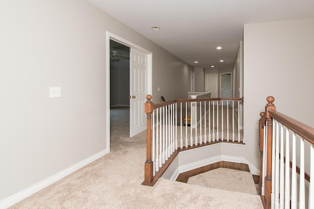 hall with carpet floors, recessed lighting, baseboards, and an upstairs landing