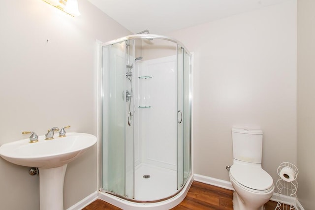 full bathroom featuring toilet, a shower stall, baseboards, and wood finished floors