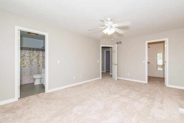 unfurnished bedroom with ensuite bathroom, carpet floors, visible vents, baseboards, and a walk in closet