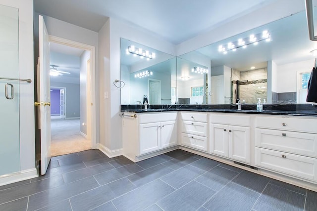 full bathroom featuring double vanity, visible vents, baseboards, a shower stall, and a sink