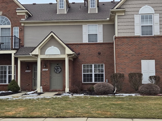 townhome / multi-family property with a front yard and brick siding