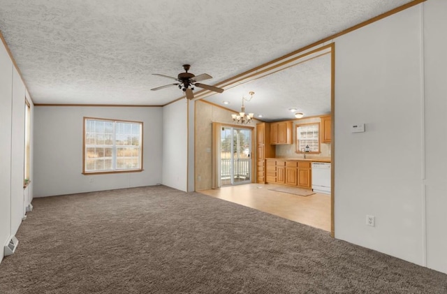 unfurnished living room featuring light carpet, a sink, a textured ceiling, and a wealth of natural light