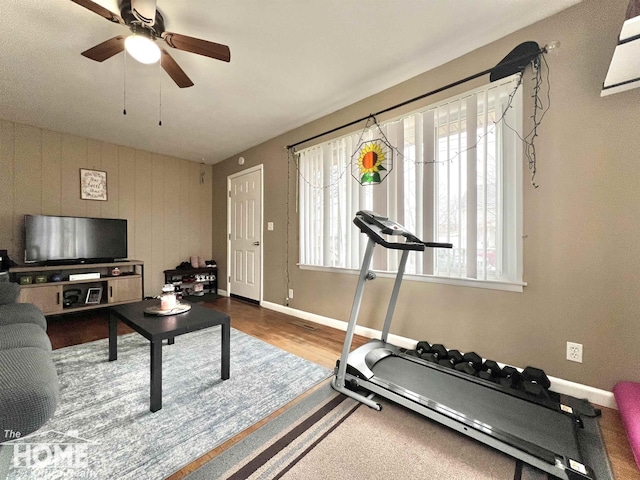 workout area with wood finished floors, a ceiling fan, and baseboards