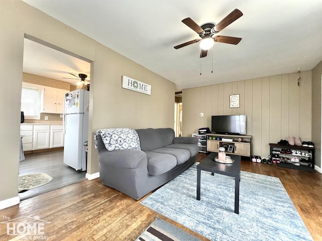 living area with ceiling fan, wood finished floors, and baseboards