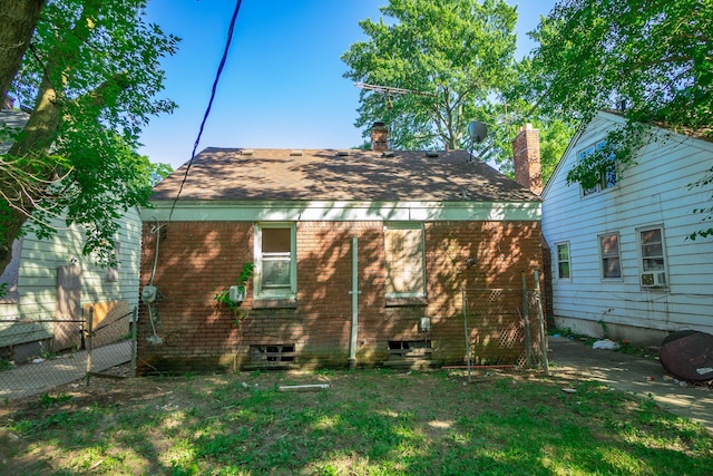 rear view of property featuring a yard, brick siding, and fence