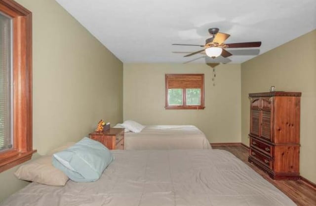 bedroom with wood finished floors, a ceiling fan, and baseboards