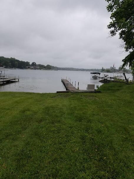 view of dock with a water view and a yard