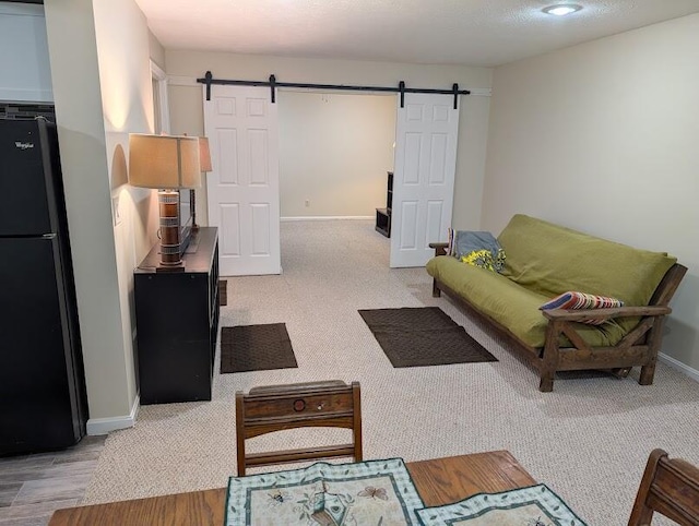 carpeted living area featuring baseboards and a barn door