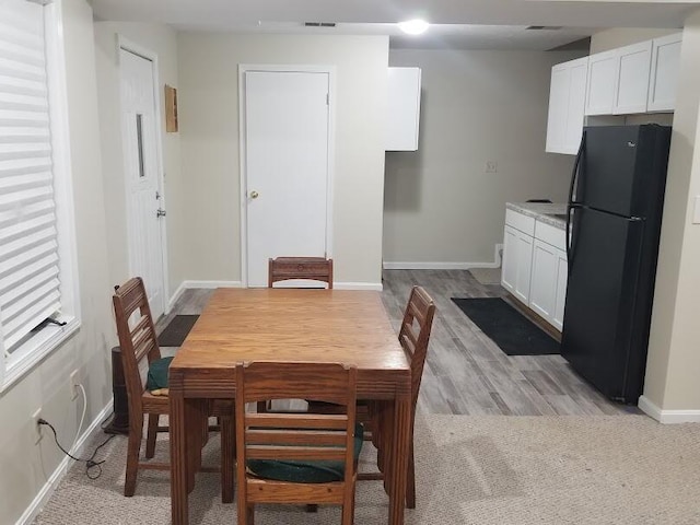 dining area featuring light wood-style flooring, visible vents, and baseboards