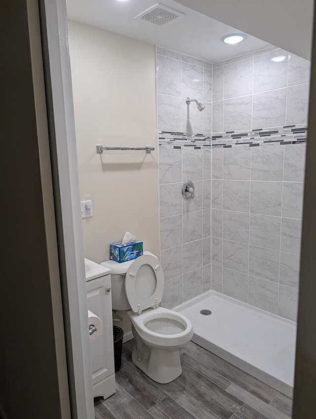 bathroom featuring toilet, wood finished floors, vanity, visible vents, and a shower stall