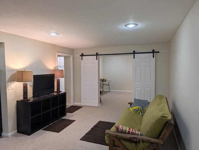 carpeted living room featuring a textured ceiling, a barn door, and baseboards