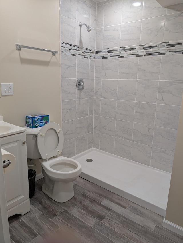 bathroom featuring toilet, a shower stall, wood finished floors, and vanity