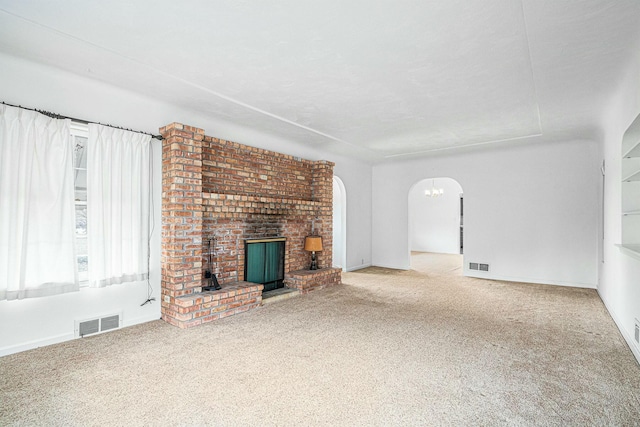 unfurnished living room featuring carpet, visible vents, and arched walkways