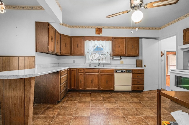 kitchen with white dishwasher, stove, brown cabinets, and light countertops