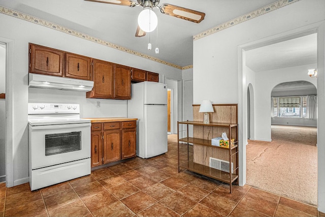 kitchen featuring under cabinet range hood, white appliances, a ceiling fan, visible vents, and dark colored carpet