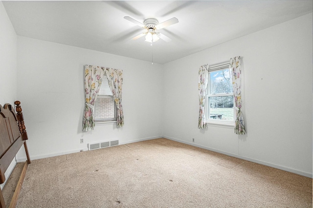 empty room featuring ceiling fan, carpet, visible vents, and baseboards