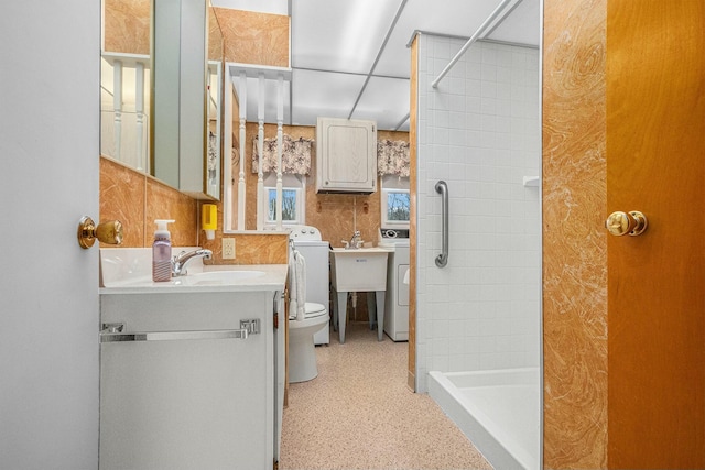 bathroom with a stall shower, decorative backsplash, toilet, vanity, and tile walls