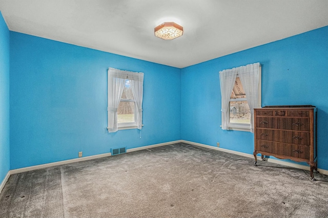 carpeted empty room with visible vents and baseboards