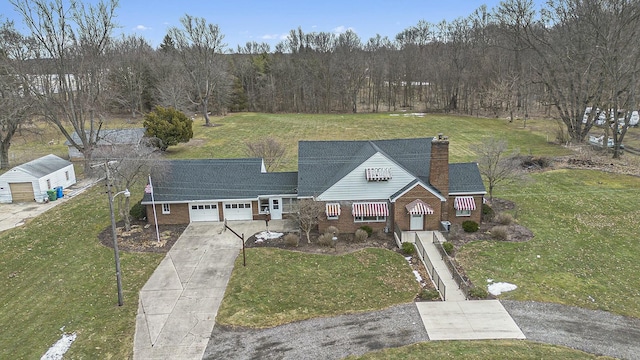 view of front of property featuring brick siding, a chimney, a garage, driveway, and a front lawn