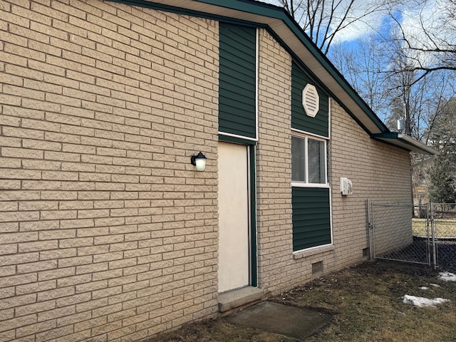 view of property exterior featuring brick siding, crawl space, fence, and a gate