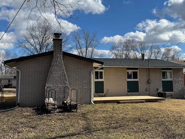 back of property with a chimney, a deck, cooling unit, a yard, and brick siding