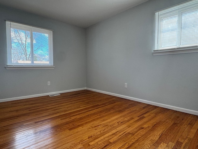 spare room featuring visible vents, baseboards, and wood finished floors