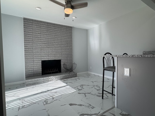 unfurnished living room with a brick fireplace, marble finish floor, ceiling fan, and baseboards