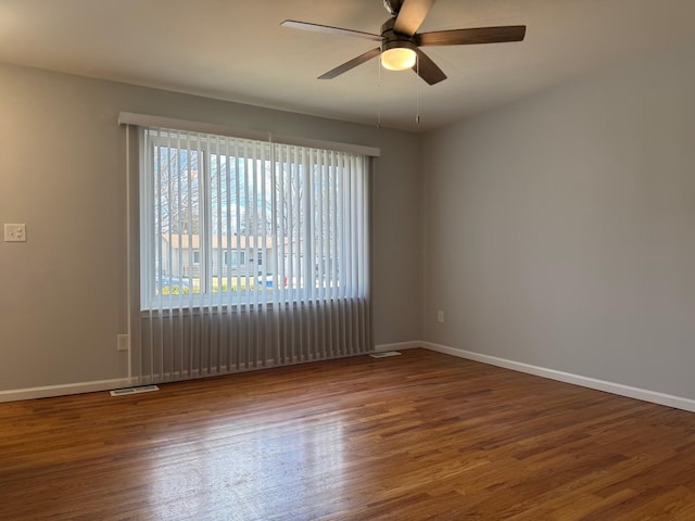 unfurnished room featuring baseboards, visible vents, and wood finished floors